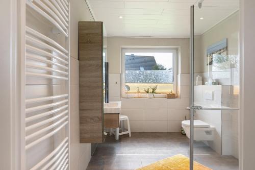 a bathroom with a toilet and a sink and a window at Gästehaus Tadenswarf in Tadenswarf