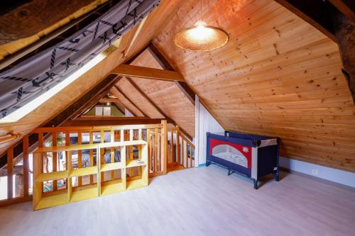 a large attic room with a tv and wooden ceilings at Loft Atypique jacuzzi sauna in Cléguérec