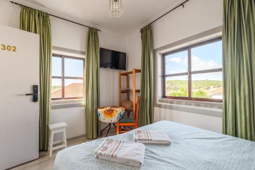 a bedroom with a bed and two windows at Aquedarte in Lisbon