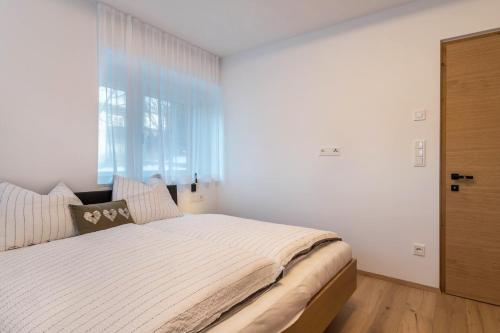 a bedroom with a large bed with a large window at Mountain Meadows Apt 4 in Valdaora