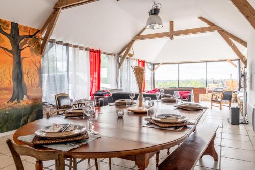a dining room with a wooden table and chairs at Gîte Le Jardin d'Eden in Bovel