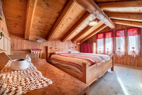 a bedroom with a bed in a room with wooden ceilings at Baita Mas Sternai Nel Parco in Bagni di Rabbi