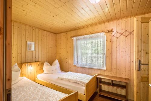 two beds in a room with wooden walls and a window at Ferienhaus Lausekuppe Neustadt in Neustadt