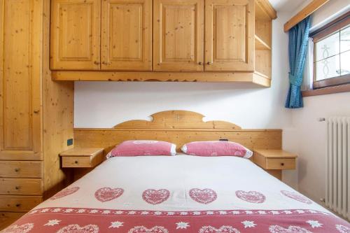 a bedroom with a bed and wooden cabinets at Residence Larice Bianco App n6 in Campodolcino
