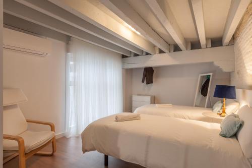 a bedroom with two beds and a chair and a window at Orbyz in Seville