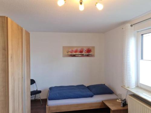 a bedroom with a bed with blue sheets and a window at Ferienwohnung Dörnbergblick Klinge in Calden