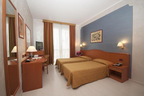 a hotel room with two beds and a desk at Hotel Brindor in Poirino