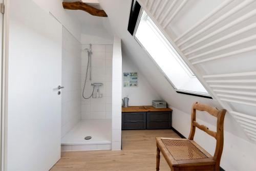 ein Badezimmer im Dachgeschoss mit Dusche und einem Holzstuhl in der Unterkunft Room 24 in Behrendorf