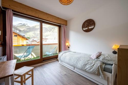 a bedroom with a bed and a large window at La maison d’Anthelmette in Valloire
