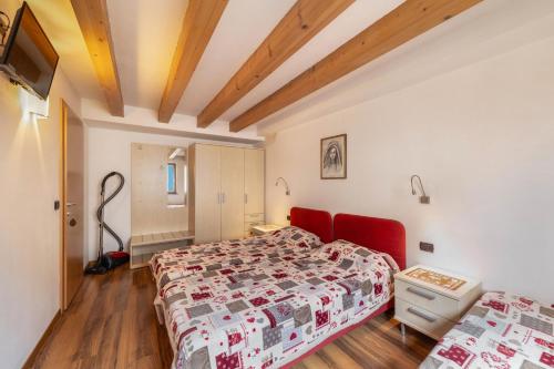 a bedroom with two beds and a red couch at Apartment Latemar Casa Alma in Tesero