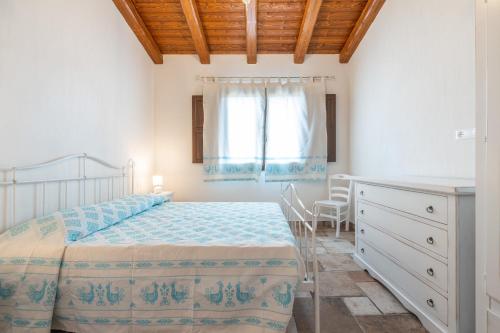 a bedroom with a bed and a dresser and a window at Villa Tramonto in Villasimius