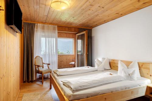 a bedroom with two beds and a chair in it at Haus Vögel in Sibratsgfäll