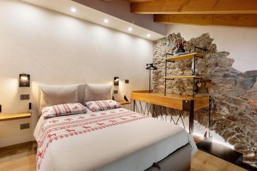 a bedroom with a bed and a stone wall at Chez Margot Et Sophie in Torgnon