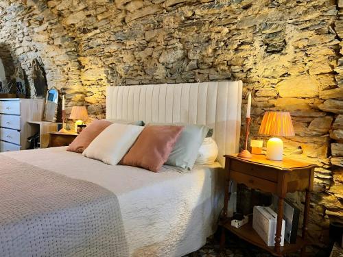 a bedroom with a bed and a stone wall at Maison D'hôtes Casa Ghjunca in Rapale