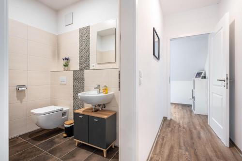 ein Badezimmer mit weißer Toilette und Waschbecken in der Unterkunft Jever Auszeit in Jever
