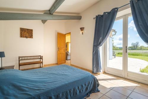 a bedroom with a blue bed and a sliding glass door at La Bellimure in Saint-Christol