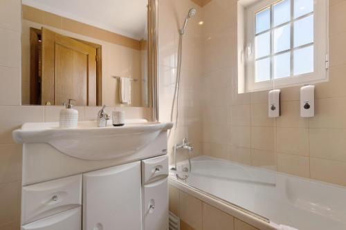 a white bathroom with a sink and a bath tub at Vivenda De São Marcos in Cacém