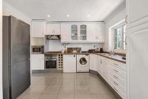 a white kitchen with white cabinets and a dishwasher at Vivenda De São Marcos in Cacém