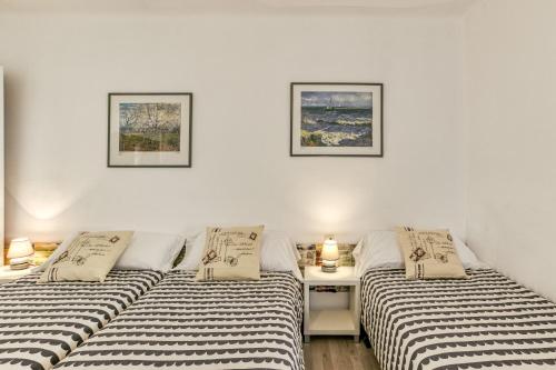 two beds in a room with a table and two pictures at Can Picola in Capmany