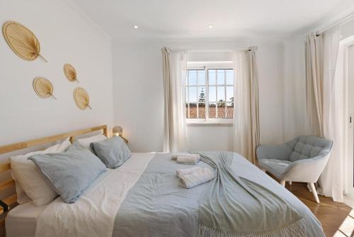 a white bedroom with a large bed and a chair at Vivenda De São Marcos in Cacém