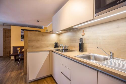 a kitchen with white cabinets and a sink at Ciasa Rungg App Corones in San Vigilio Di Marebbe