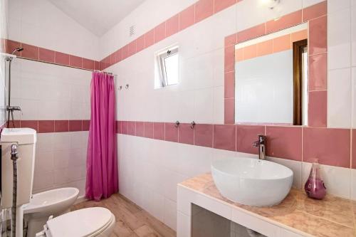 a bathroom with a sink and a toilet and a mirror at Casa dos Jotas in Martinlongo