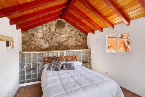 a bedroom with a bed and a stone wall at Casa Cueva in Teror