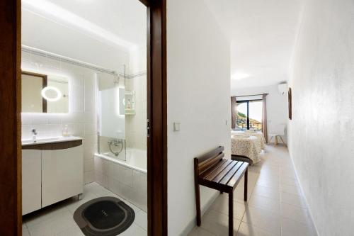 a white bathroom with a bench and a sink at Apartamento Mar-colina-sol in Carvoeiro