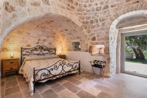 a bedroom with a bed in a stone wall at Trulli House in Putignano