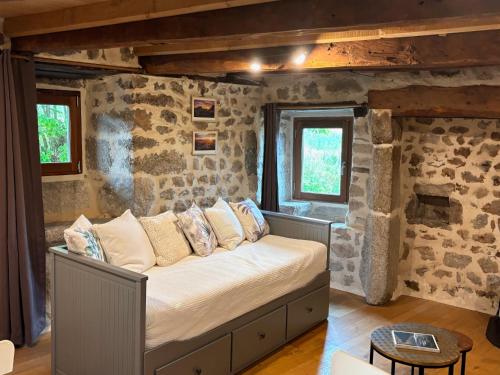 a bedroom with a bed in a stone wall at Le Chant du Grillon in Le Nayrac