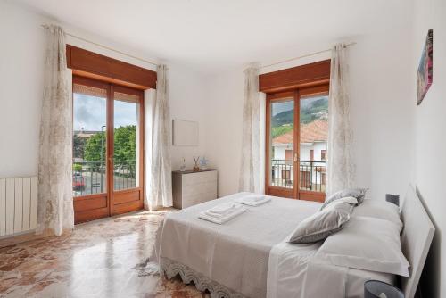 a white bedroom with a bed and large windows at Zio Gennaro Residence in Agerola