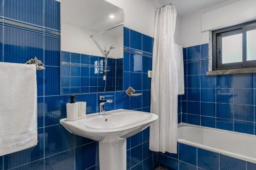a blue tiled bathroom with a sink and a tub at Birre House in Cascais