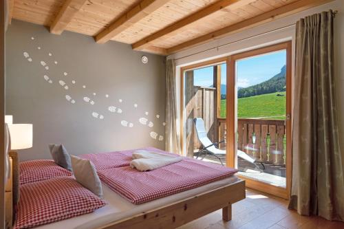 a bedroom with a bed and a balcony with a view at Schererhof Morgenrot in Castelrotto