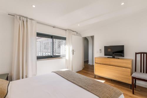 a bedroom with a bed and a flat screen tv at Birre House in Cascais