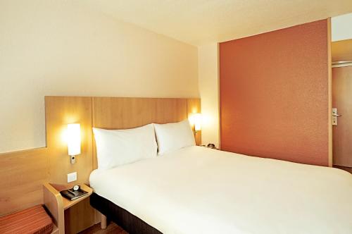 a large bed in a hotel room with two lamps at ibis Porto Centro São Bento in Porto