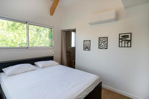 a bedroom with a white bed and a window at Escapade Tout Confort - Seignosse in Seignosse