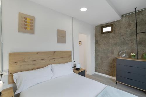 a bedroom with a white bed and a brick wall at El Alpendre in Moya