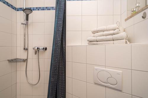 a white tiled bathroom with a shower and towels at Appartment Panoramablick in Oberteuringen