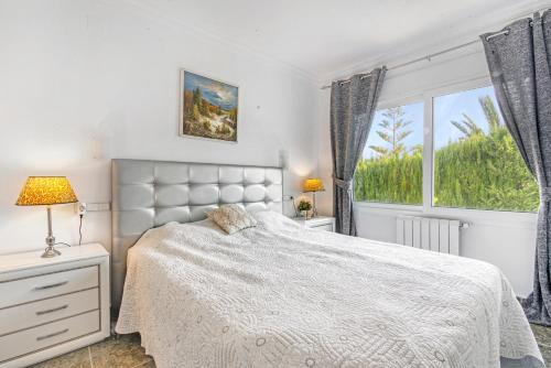 a bedroom with a white bed and a window at Bohemia in Jávea