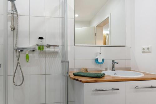 a white bathroom with a shower and a sink at Apartment am Seefischmarkt in Kiel