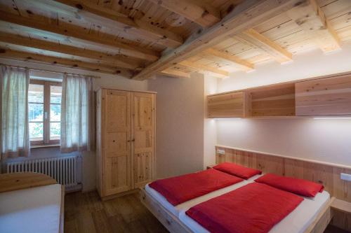 a bedroom with a bed with red sheets on it at Kaserhof in Soprabolzano