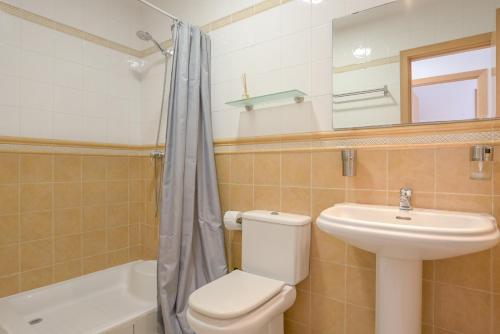 a bathroom with a toilet and a sink and a mirror at Michalete Fernando - Sólo Familias in Conil de la Frontera