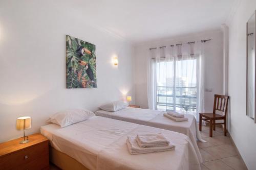 a bedroom with two beds and a chair and a window at Quarteira Beach I in Quarteira