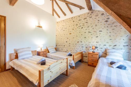 a bedroom with two beds and a stone wall at Gites les Renardiers in Peyraube