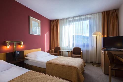 a hotel room with two beds and a television at Mercure Jelenia Góra in Jelenia Góra