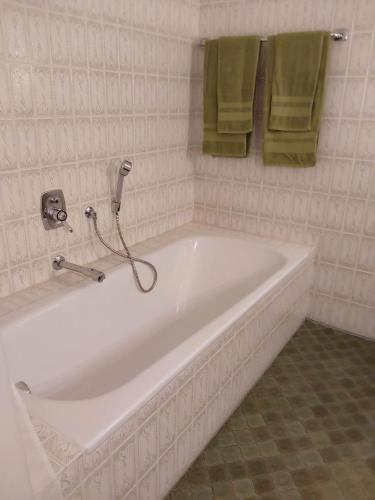 a white bath tub in a bathroom with green towels at Ferienwohnung Cipolla in Oberkirch