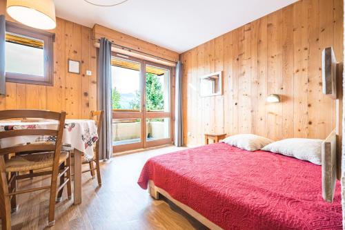 a bedroom with a red bed and wooden walls at Studio 4 - La Bruyère in Crest-Voland
