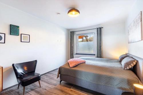 a bedroom with a bed and a chair at Suiten im Alten Berghotel Antonia in Eslohe