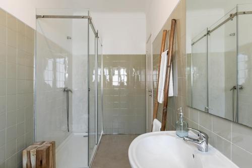 a white bathroom with a sink and a shower at Casa das Alfazemas in Cadaval