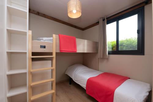 a bedroom with bunk beds and a bed with a window at Chalet 35m2 - Armen in Plouhinec